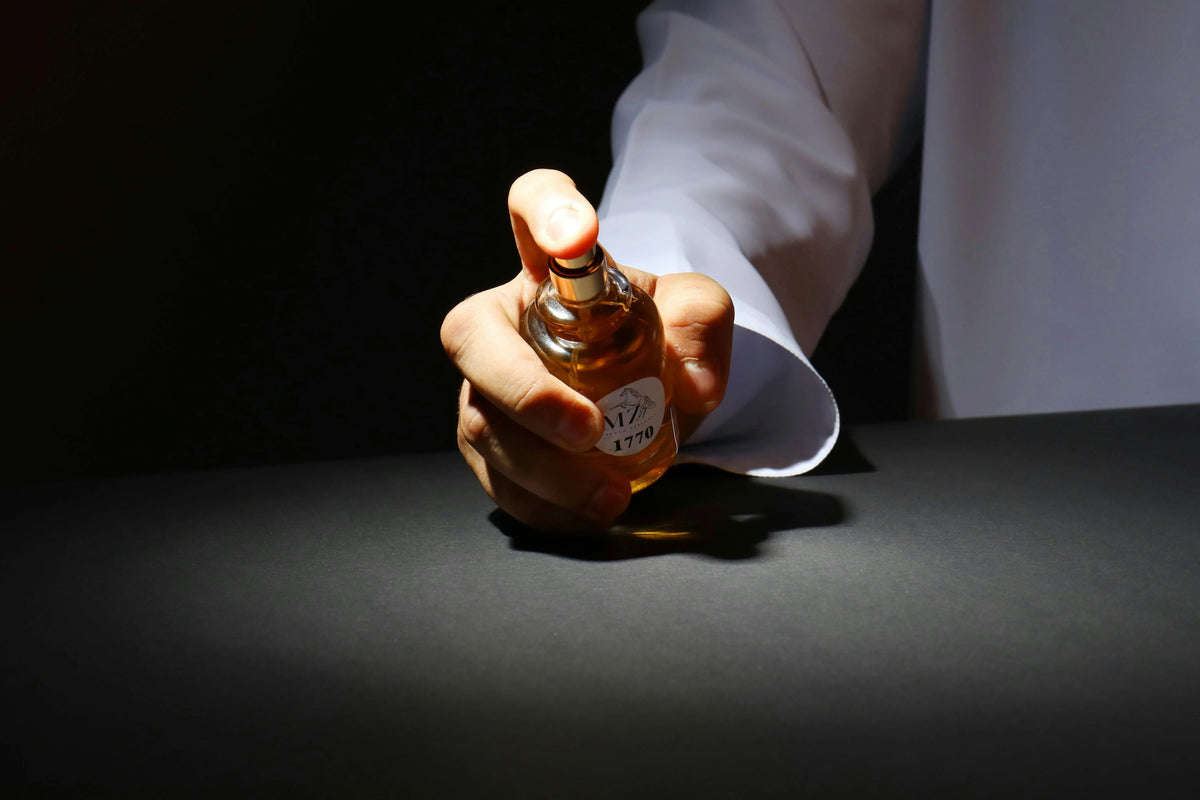 MOJ men's perfume bottle in a black table in hands of a white shirt wearing men
