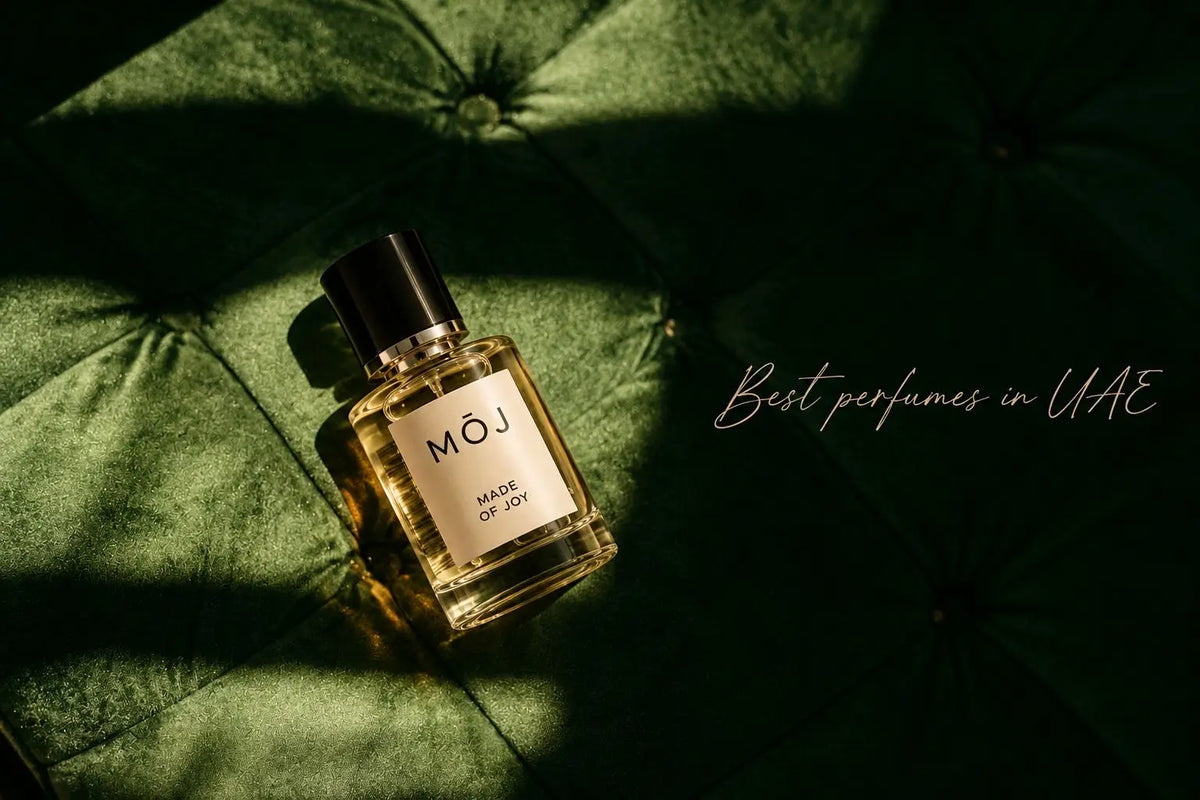 MOJ Made of Joy perfume bottle with black cap lying on green tufted velvet in a beam of sunlight, with the words Best perfumes in UAE in script