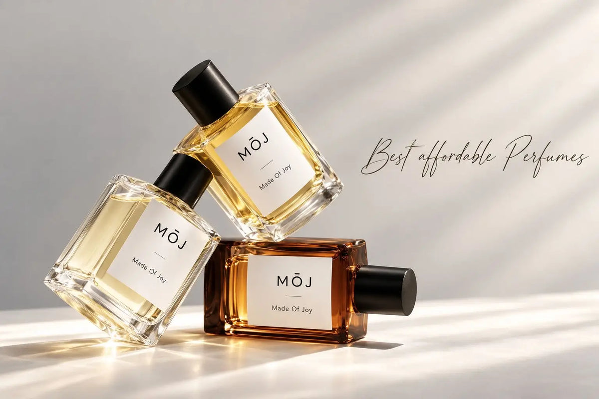 Three MOJ perfume bottles with black caps stacked in sunlight, one amber and two pale gold, next to the words Best affordable Perfumes