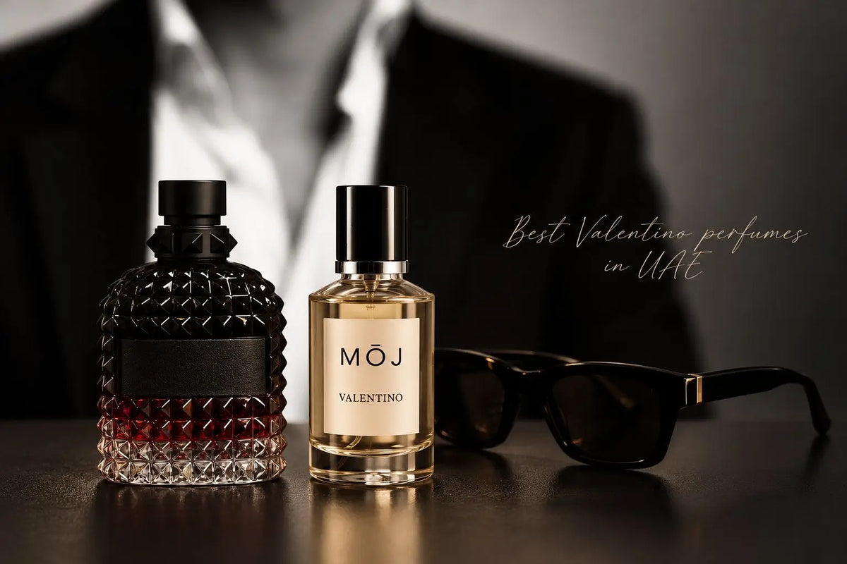 MOJ Valentino bottle beside a black studded Valentino Uomo Born in Roma Intense bottle and dark sunglasses on a table, a man in a black suit behind, Best Valentino Perfumes in UAE