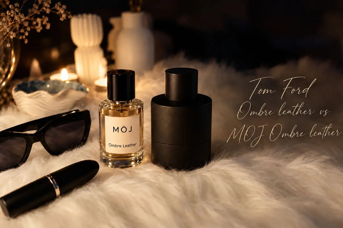 MOJ Ombre Leather perfume bottle beside a matte black Tom Ford Ombre Leather bottle on white fur with candles, sunglasses and a lipstick